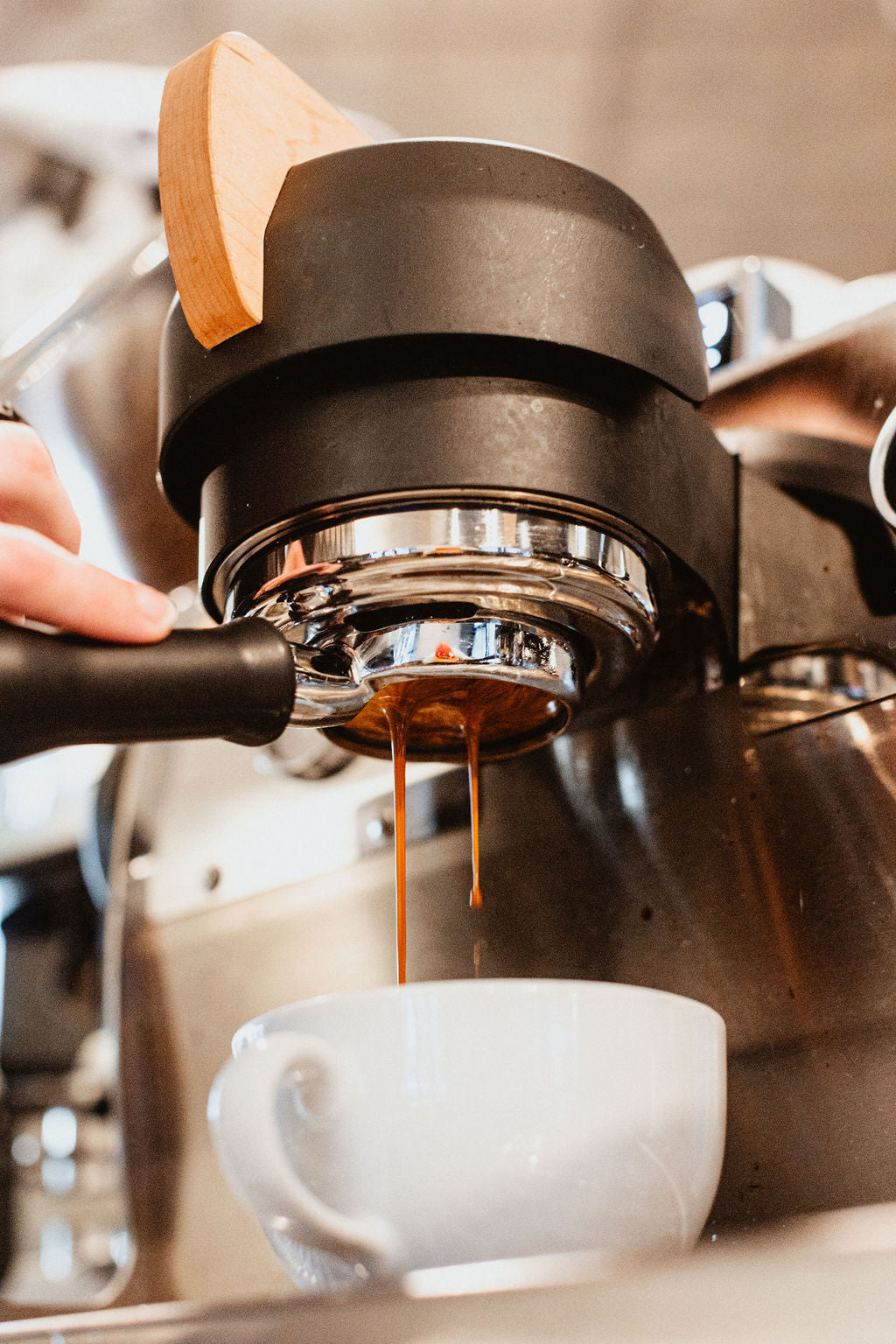 Close-up of espresso being expertly pulled from a professional machine at Black Sheep Coffee, with rich, golden-brown coffee streaming into a white ceramic cup. The shot highlights the craftsmanship behind each cup and the high-quality equipment used to deliver the perfect espresso shot. Keywords: Black Sheep Coffee espresso, artisan coffee brewing, coffee shop espresso pull, handcrafted espresso.